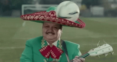 A Man Wearing A Green Suit And Sombrero Is Playing A Guitar . GIF