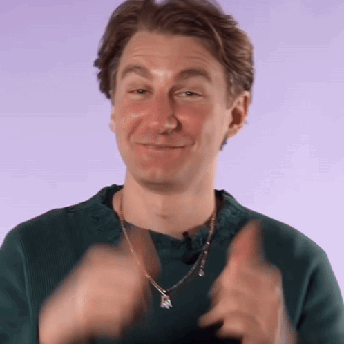 A Man Wearing A Green Sweater And A Necklace Is Clapping GIF