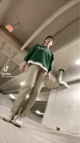 a man wearing a green sweater and khaki pants is standing in a garage .