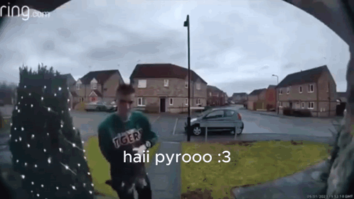 A Man Wearing A Green Tiger Sweatshirt Is Standing In Front Of A Ring Doorbell GIF