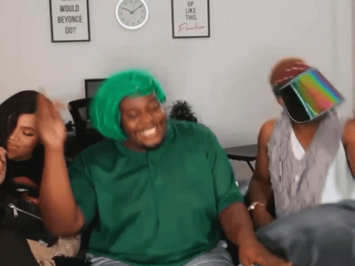 A Man Wearing A Green Wig Is Laughing In Front Of A Sign That Says Would Beyonce Do GIF