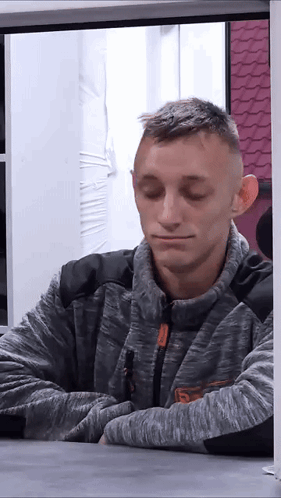 A Man Wearing A Grey Sweater With The Letter S On It GIF