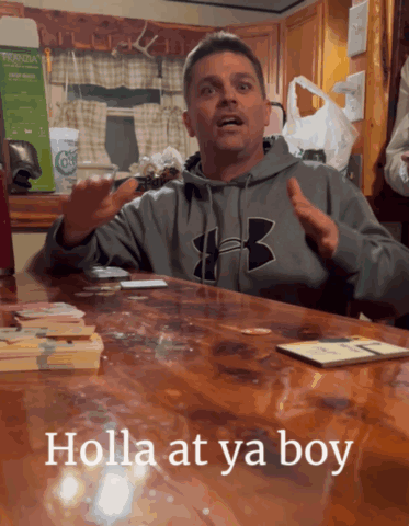 A Man Wearing A Grey Under Armour Sweatshirt Sitting At A Table GIF