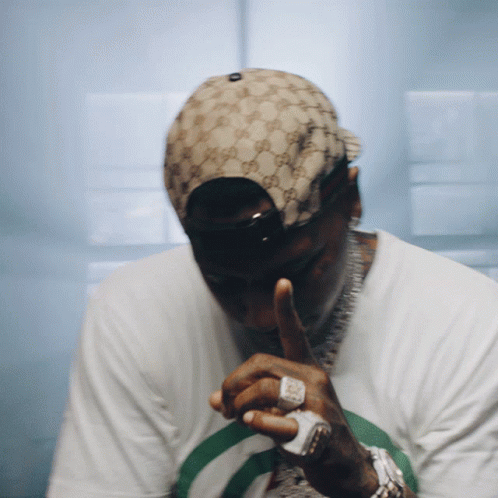 A Man Wearing A Gucci Hat Is Covering His Mouth With His Hand GIF