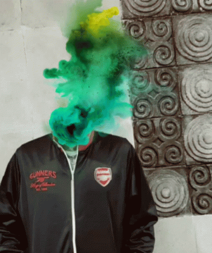 A Man Wearing A Gunners Jacket Has Green Smoke Coming Out Of His Face GIF