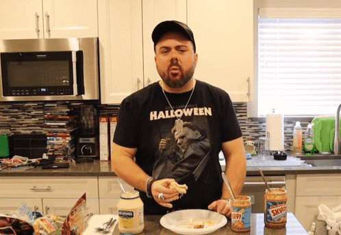 A Man Wearing A Halloween T-Shirt Is Cooking GIF
