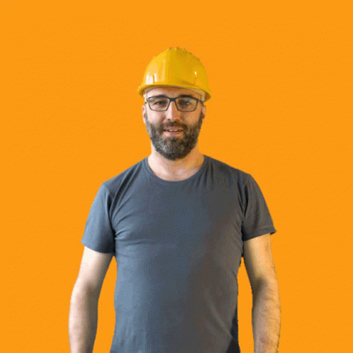 A Man Wearing A Hard Hat And Glasses Holds His Fist Up In The Air GIF