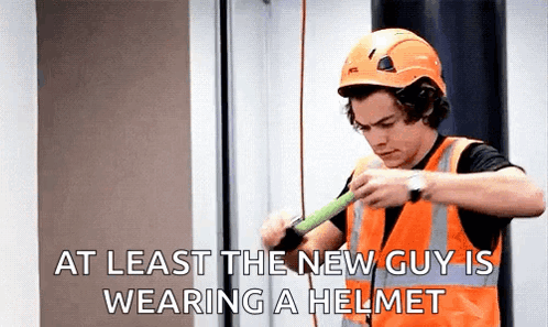 A Man Wearing A Hard Hat And Safety Vest Is Holding A Tape Measure . GIF