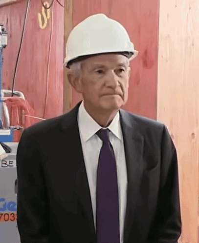 A Man Wearing A Hard Hat Stands In Front Of A Sign That Says Be GIF