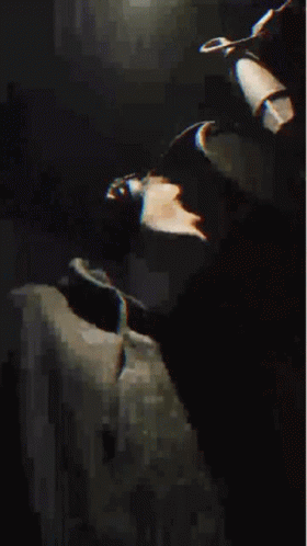 A Man Wearing A Hat And A Black Jacket Is Making A Funny Face . GIF