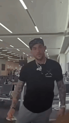 A Man Wearing A Hat And A Black Shirt With A Smiley Face On It GIF