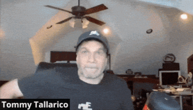 A Man Wearing A Hat And A Black Shirt With The Name Tommy Tallarico On It GIF