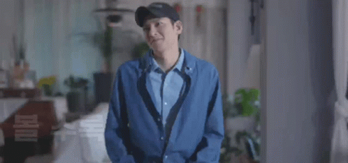 A Man Wearing A Hat And A Blue Jacket Is Smiling GIF