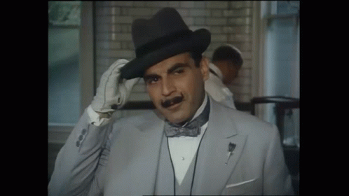 A Man Wearing A Hat And A Bow Tie Adjusts His Hat GIF