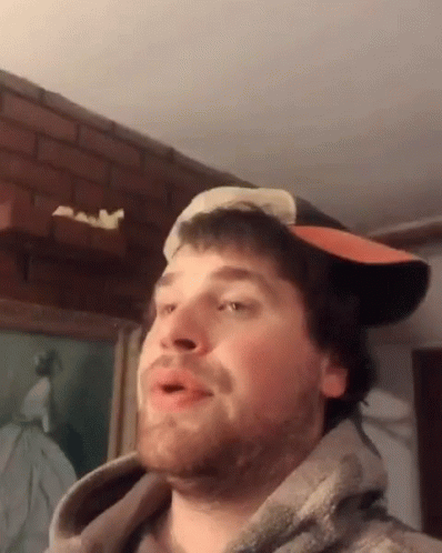 A Man Wearing A Hat And A Hoodie Is Making A Face GIF