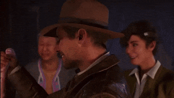 A Man Wearing A Hat And A Jacket Is Smiling In Front Of Two Other Men . GIF
