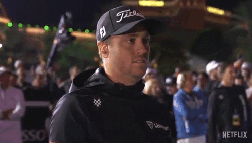 A Man Wearing A Hat And A Jacket Is Standing In Front Of A Crowd Of People . GIF