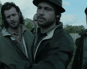 A Man Wearing A Hat And A Jacket Is Standing Next To Another Man GIF