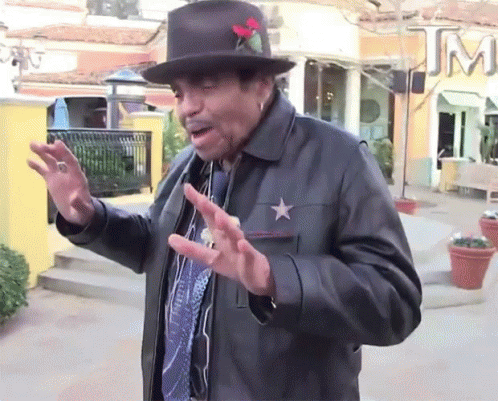 A Man Wearing A Hat And A Leather Jacket Has A Star On His Chest GIF