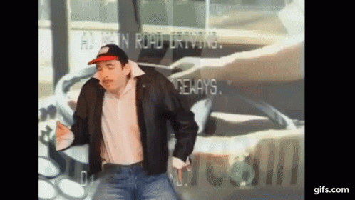 A Man Wearing A Hat And A Leather Jacket Is Dancing In Front Of A Sign That Says ' A ' On It GIF