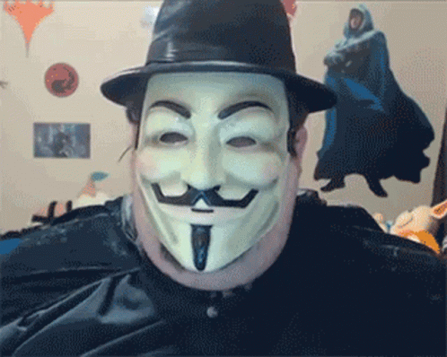 A Man Wearing A Hat And A Mask Looks At The Camera GIF