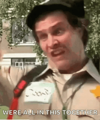 A Man Wearing A Hat And A Name Tag With The Words Were All In This Together Written On It GIF