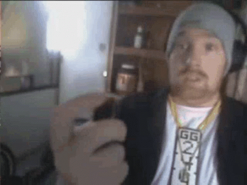 A Man Wearing A Hat And A Necklace Is Holding A Lighter In His Hand . GIF