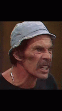 A Man Wearing A Hat And A Necklace Looks Down GIF