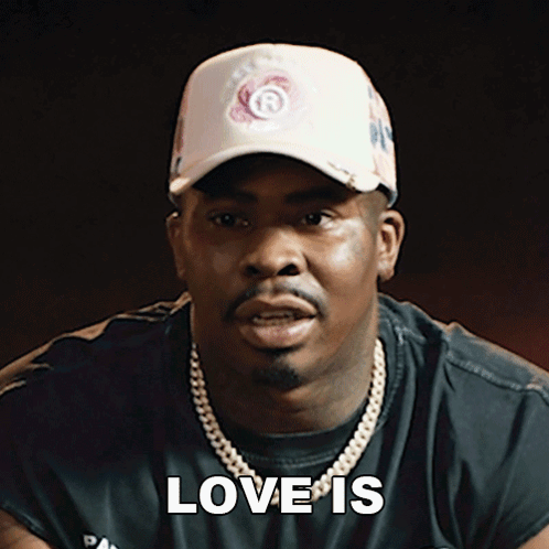 a man wearing a hat and a necklace says " love is "
