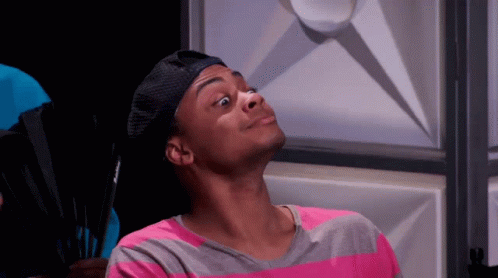 a man wearing a hat and a pink and gray striped shirt is making a face .