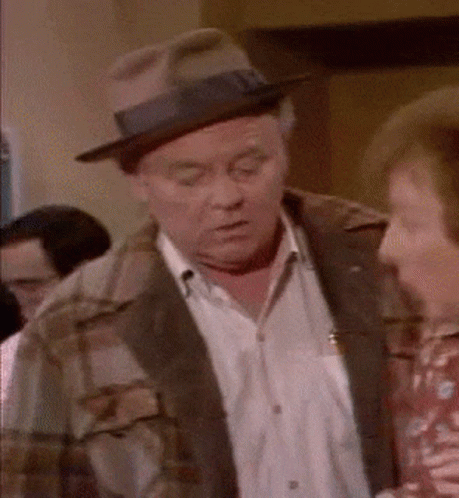 Man In Hat And Plaid Jacket Talking To Woman GIF