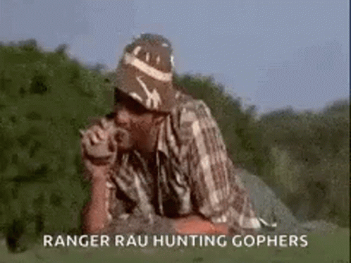 A Man Wearing A Hat And A Plaid Shirt Is Smoking A Cigarette And Drinking From A Cup . GIF