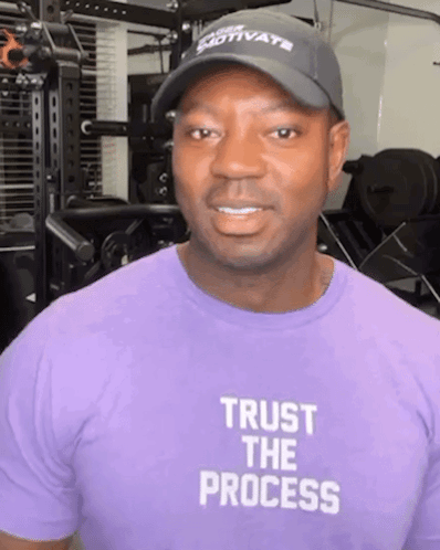A Man Wearing A Hat And A Purple Shirt That Says Trust The Process GIF