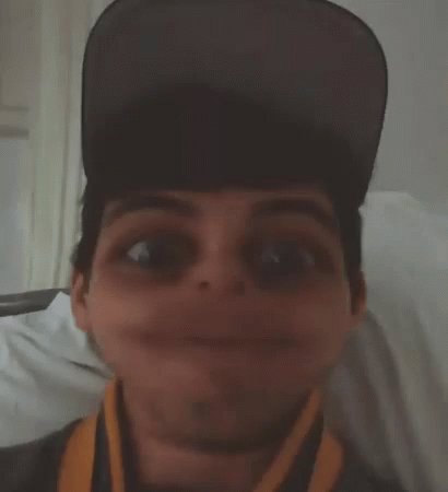 a man wearing a hat and a scarf makes a funny face