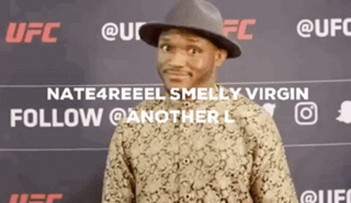 A Man Wearing A Hat And A Shirt Is Standing In Front Of A Ufc Sign . GIF