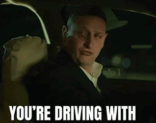 A Man Wearing A Hat And A Suit Is Driving A Car GIF