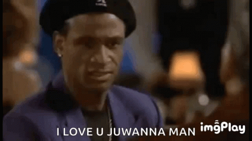 A Man Wearing A Hat And A Suit Is Talking To Another Man In A Bar . GIF