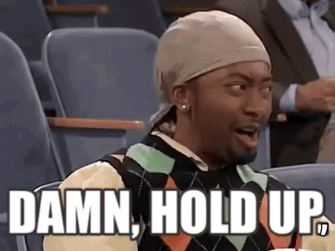 A Man Wearing A Hat And A Sweater Is Sitting In A Stadium With The Words `` Damn , Hold Up '' . GIF