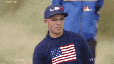 A Man Wearing A Hat And A Sweater With An American Flag On It GIF