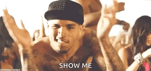 A Man Wearing A Hat And A Tank Top Is Dancing In Front Of A Crowd And Says `` Show Me '' . GIF