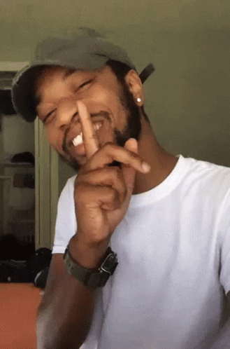 A Man Wearing A Hat And A Watch Is Making A Shhh Gesture GIF