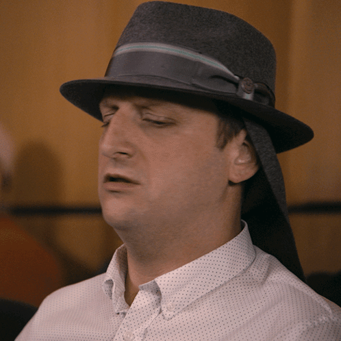 A Man Wearing A Hat And A White Shirt Looks Tired GIF