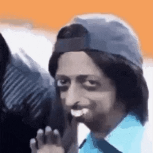 A Man Wearing A Hat And A Wig Is Smiling And Waving . GIF