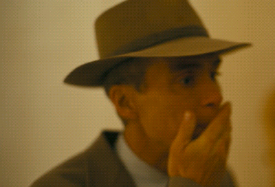 A Man Wearing A Hat And Covering His Mouth GIF