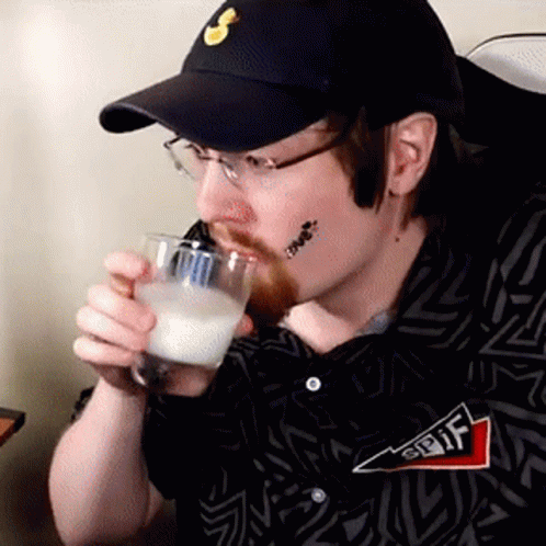 A Man Wearing A Hat And Glasses Is Drinking From A Glass . GIF