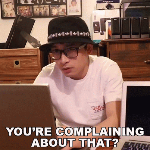 A Man Wearing A Hat And Glasses Is Sitting In Front Of A Laptop And Says You 'Re Complaining About That ? GIF
