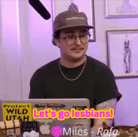A Man Wearing A Hat And Glasses Is Sitting In Front Of A Laptop With The Words Let 'S Go Lesbians On It . GIF