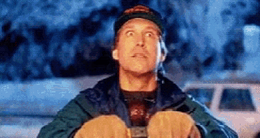 a man wearing a hat and gloves is looking up at the sky while holding something in his hands .