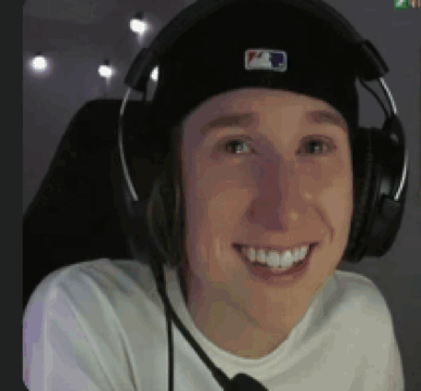 a man wearing a hat and headphones is smiling .