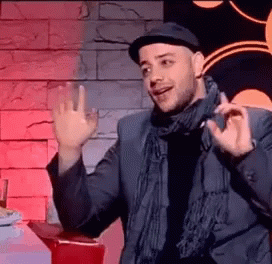 A Man Wearing A Hat And Scarf Is Giving A Thumbs Up Sign . GIF
